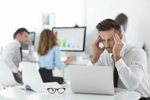 Mann mit Kopfschmerzen am Arbeitsplatz